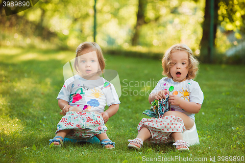 Image of The two little baby girls sitting on pots