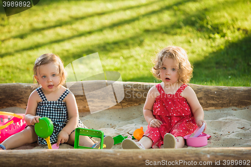 Image of The two little baby girls playing toys in sand