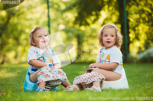 Image of The two little baby girls sitting on pots