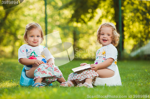 Image of The two little baby girls sitting on pots