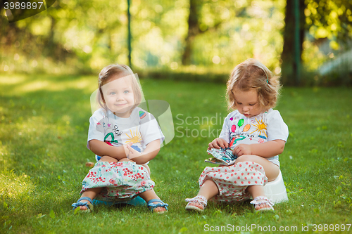 Image of The two little baby girls sitting on pots