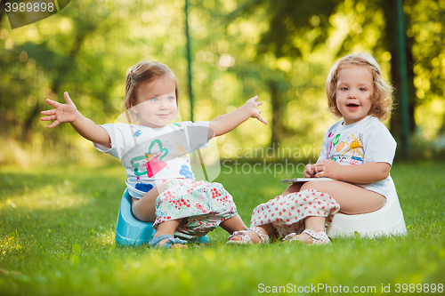 Image of The two little baby girls sitting on pots
