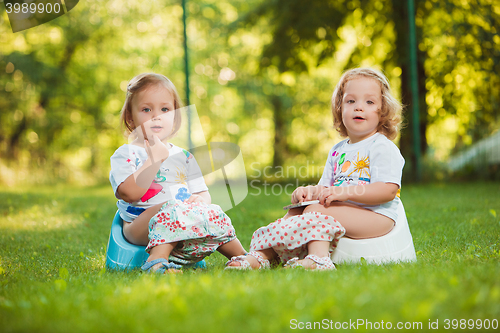 Image of The two little baby girls sitting on pots