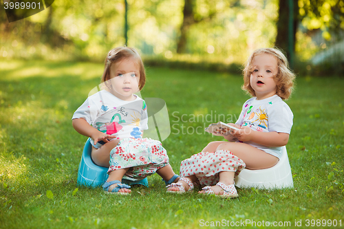 Image of The two little baby girls sitting on pots