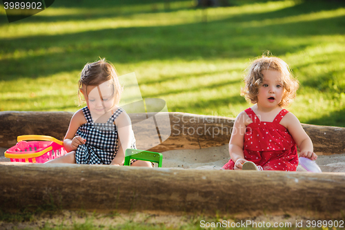 Image of The two little baby girls playing toys in sand