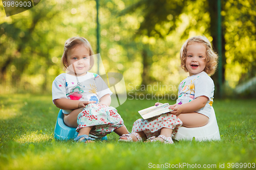 Image of The two little baby girls sitting on pots