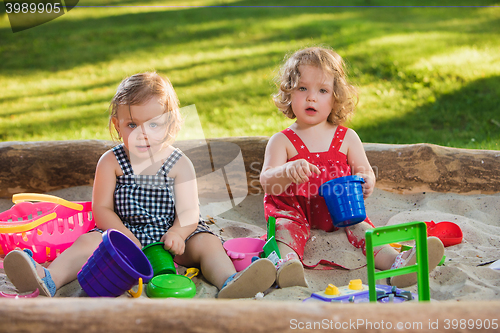 Image of The two little baby girls playing toys in sand