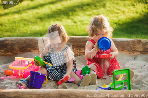 Image of The two little baby girls playing toys in sand