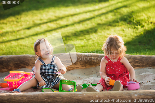 Image of The two little baby girls playing toys in sand