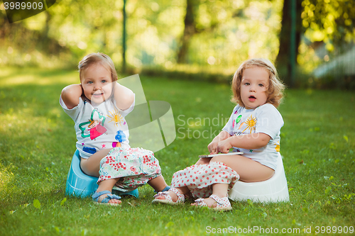 Image of The two little baby girls sitting on pots