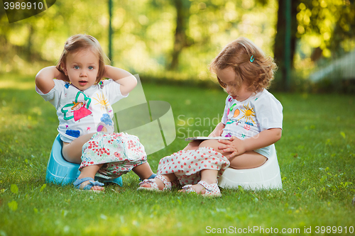 Image of The two little baby girls sitting on pots