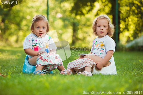 Image of The two little baby girls sitting on pots