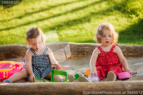 Image of The two little baby girls playing toys in sand