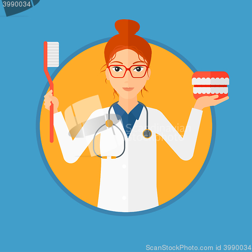 Image of Dentist with dental jaw model and toothbrush.
