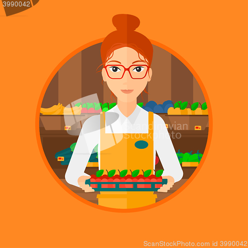 Image of Supermarket worker with box full of apples.