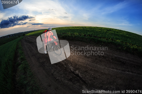 Image of Mountain bikeer rides on the trail against beautiful sunset