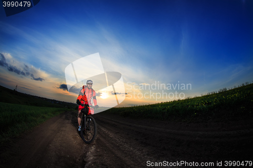 Image of Mountain bikeer rides on the trail against beautiful sunset