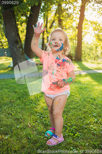 Image of Two-year old girl stained in colors against green lawn