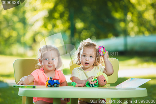 Image of The two little baby girls playing toys in sand