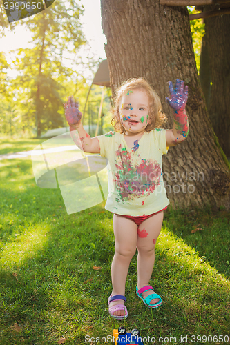 Image of Two-year old girl stained in colors against green lawn