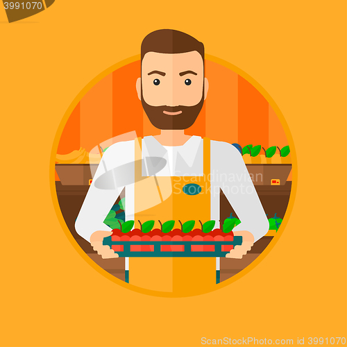 Image of Supermarket worker with box full of apples.