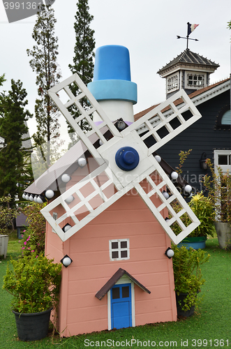 Image of Small wooden mill standing on the green grass 