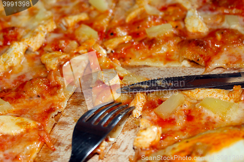 Image of appetizing pizza cut by knife and fork