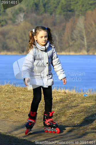 Image of young girl goes in roller skates on the ground