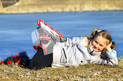 Image of young girl in roller skates lays on the ground