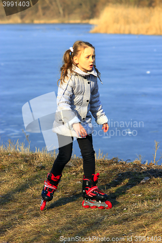 Image of young girl goes in roller skates on the ground