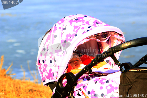 Image of little baby sleeps in perambulator near the river