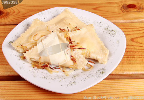 Image of Cooked raviolli with mushrooms on a shiny white plate