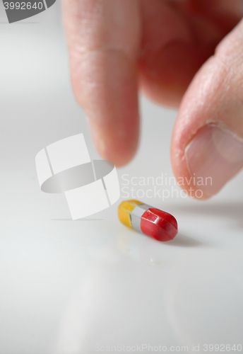 Image of hand picking up a pill