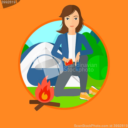Image of Woman kindling campfire.