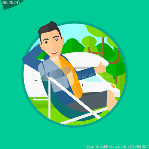 Image of Man sitting in chair in front of camper van.