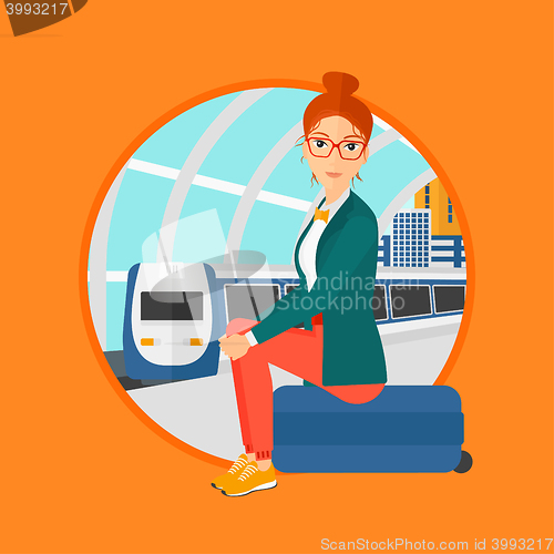 Image of Woman sitting on suitcase at the train station.