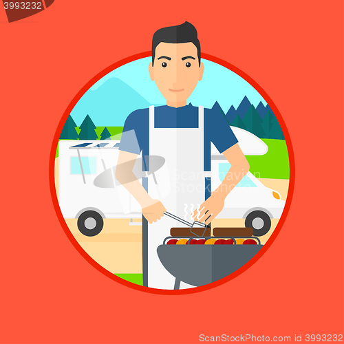 Image of Man having barbecue in front of camper van.