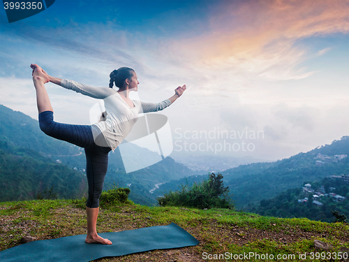 Image of Woman doing yoga asana Natarajasana outdoors at waterfall