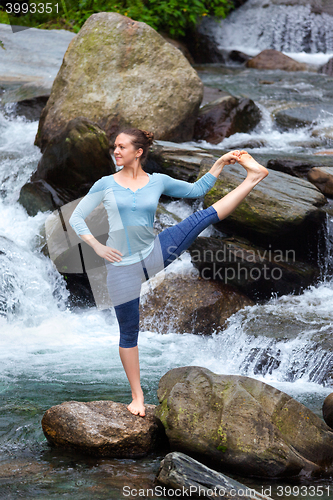 Image of Woman doing Ashtanga Vinyasa Yoga asana outdoors at waterfall