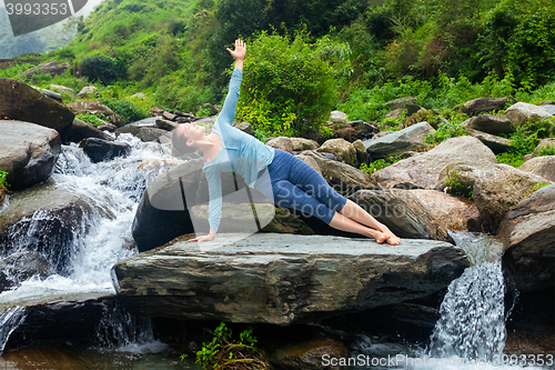 Image of Woman doing yoga asana Vasisthasana - side plank pose outdoors