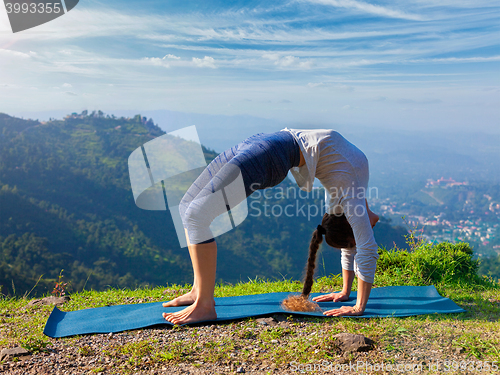 Image of Woman doing Ashtanga Vinyasa Yoga asana Urdhva Dhanurasana outdoors