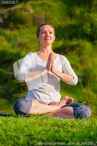 Image of Young sporty fit woman doing yoga Lotus pose oudoors 