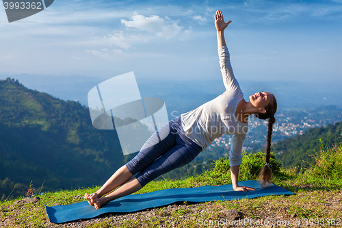 Image of Woman doing yoga asana Vasisthasana - side plank pose outdoors