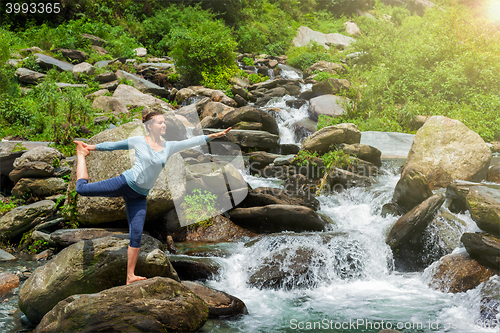 Image of Woman doing yoga asana Natarajasana outdoors at waterfall