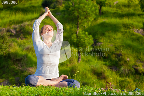 Image of Young sporty fit woman doing yoga Lotus pose oudoors 