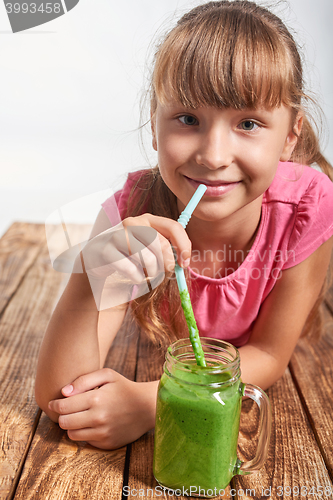 Image of Girl lying on wooden floor and drinking green smoothie