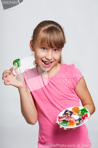 Image of Happy little girl holding a plate with colorful jelly candies