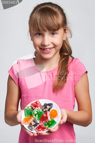 Image of Happy little girl holding a plate with colorful jelly candies