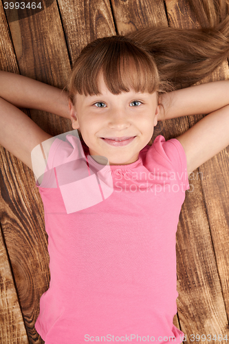 Image of Top view of a smiling little girl lying on back