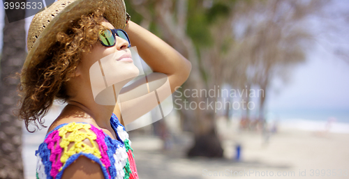 Image of Woman in sunglasses and hat outside looking up